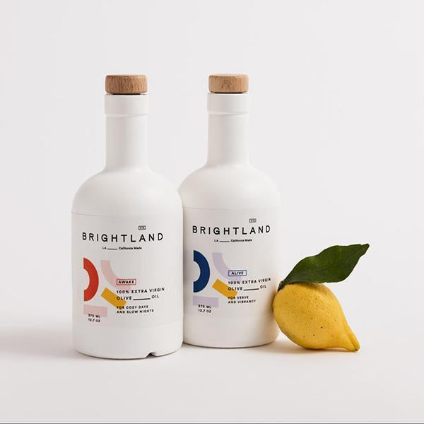 a bottle of awake and a bottle of alive brightland oils next to a lemon