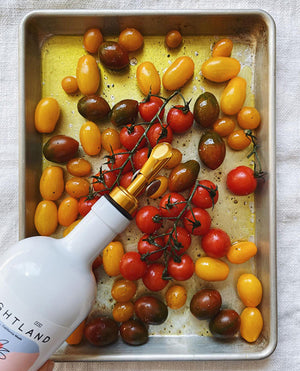 a bottle of brightland oil being poured onto vegetables on a baking sheet