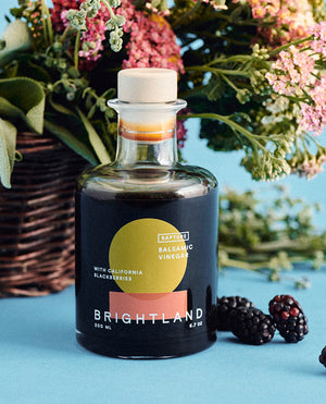 a bottle of brightland rapture balsamic vinegar with flowers and blackberries