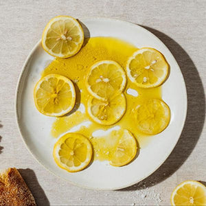 a couple pieces of bread next to a plate of lemons sitting in oil