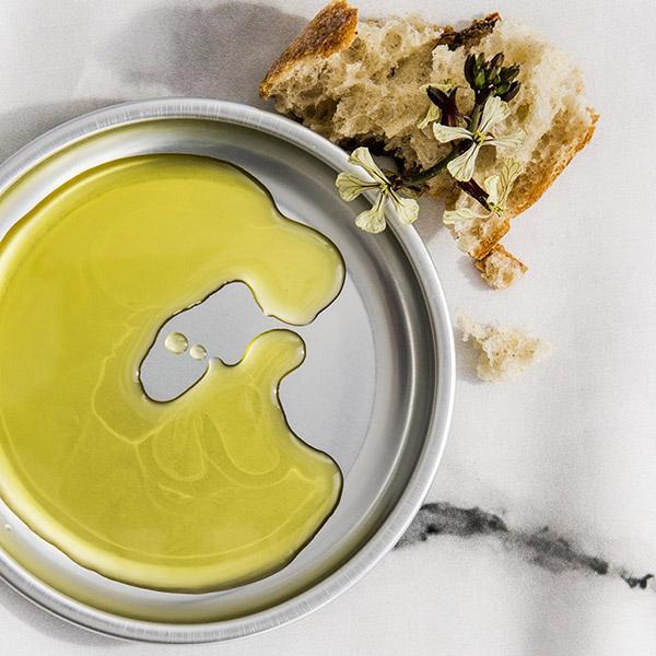 a plate with oil next to a piece of garnished bread