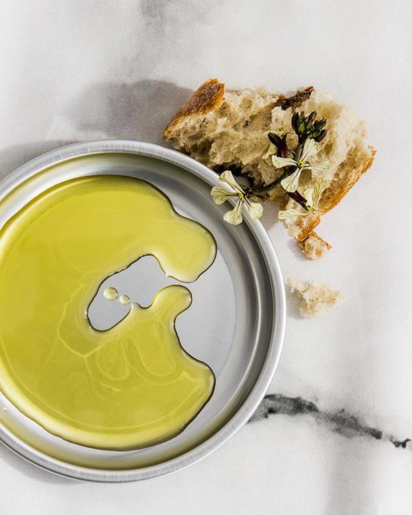 a piece of bread next to a plate with oil for dipping