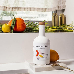 a bottle of brightland oil on a counter with fresh citrus